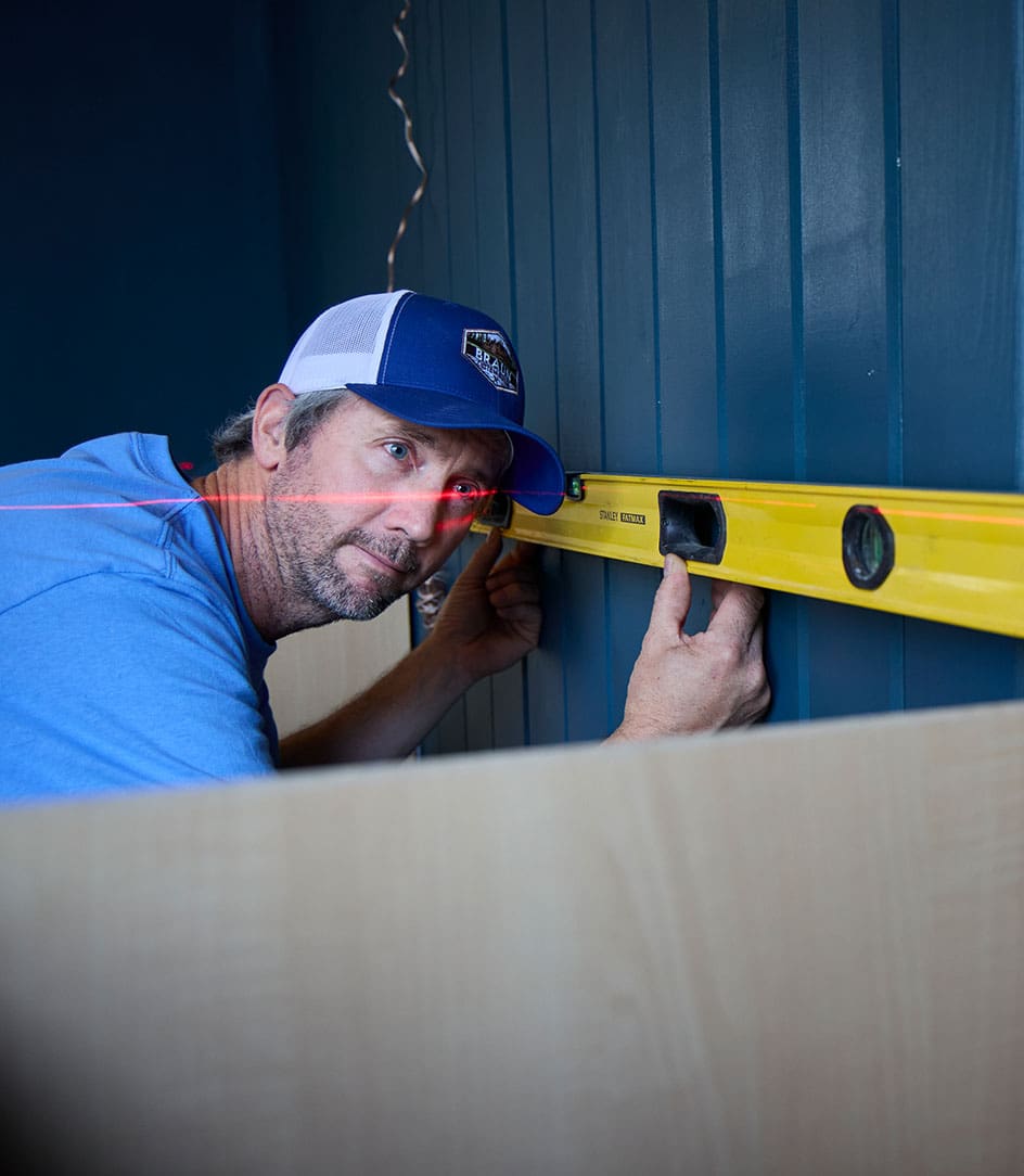 Braun Custom Builds crew member checking level with a laser and spirit level